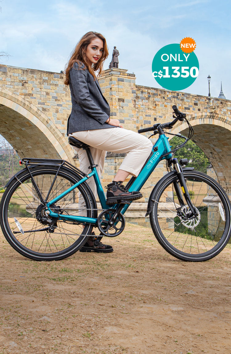 A woman rides a Fiido C11 electric bike by the river under a bridge.